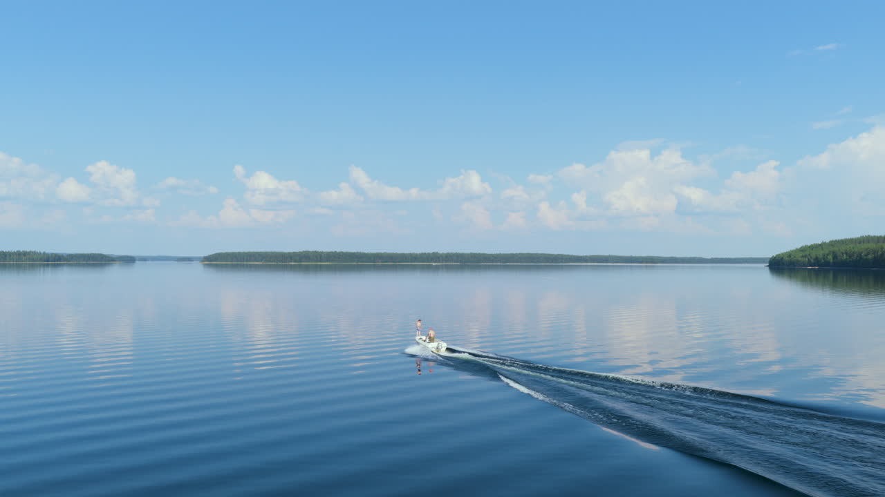 Drone tracking a boat driving on reflecting lake Saimaa, summer day in Finland