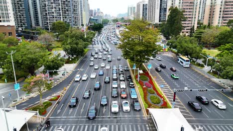 aerial view of a bustling city street in shenzhen, china, showcasing heavy traffic, organized lanes, and urban greenery. the scene captures modern infrastructure, daily commute, and urban movement.