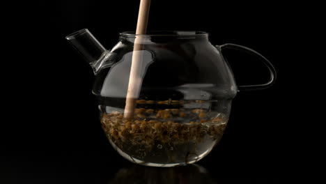 una tetera de madera que agita el agua y el té suelto