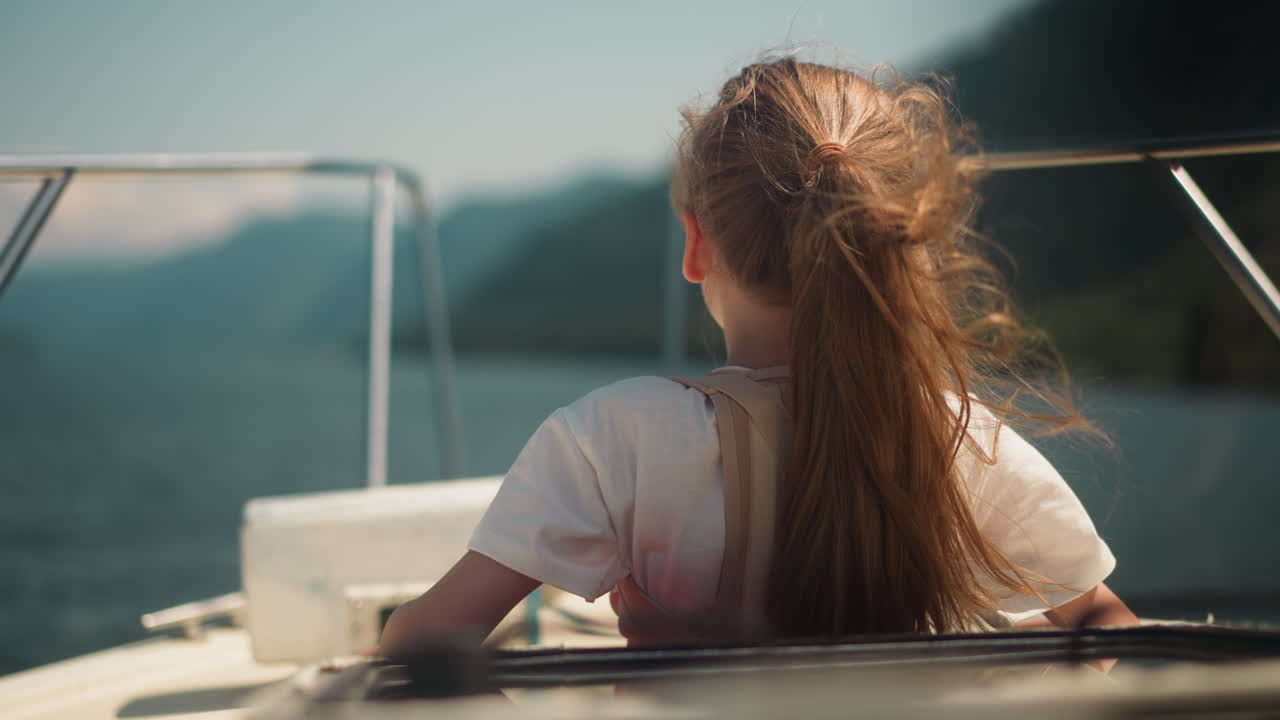 Girl with orthopedic corset looks in distance riding motorboat in sea bay backside view. Child with back injury rests on yacht in ocean on summer day