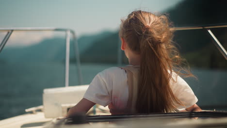 girl with orthopedic corset looks in distance riding motorboat in sea bay backside view. child with back injury rests on yacht in ocean on summer day