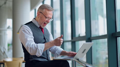freelance senior man working on a laptop. mature man becomes happy after doing a successful job on a computer at home.