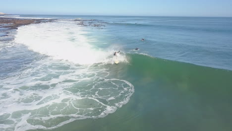 dramatic aerial of surfing along coast in south africa