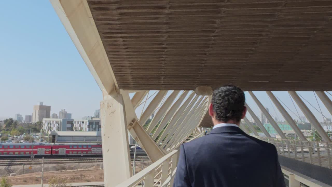 Empresario caminando por un puente con un tren de fondo.