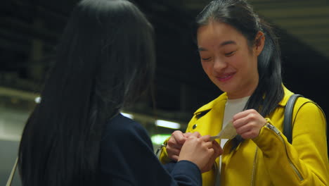 Two-Young-Female-Friends-Looking-At-Photos-On-Underground-Train-Station-Platform