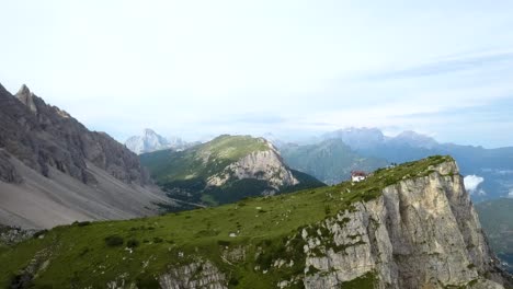 Aerial-of-a-small-house-on-a-cliff-mountain-ridge,-dolomites-italy