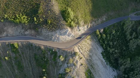 SUV-drives-on-winding-mountain-road-crossing-from-light-into-shadows