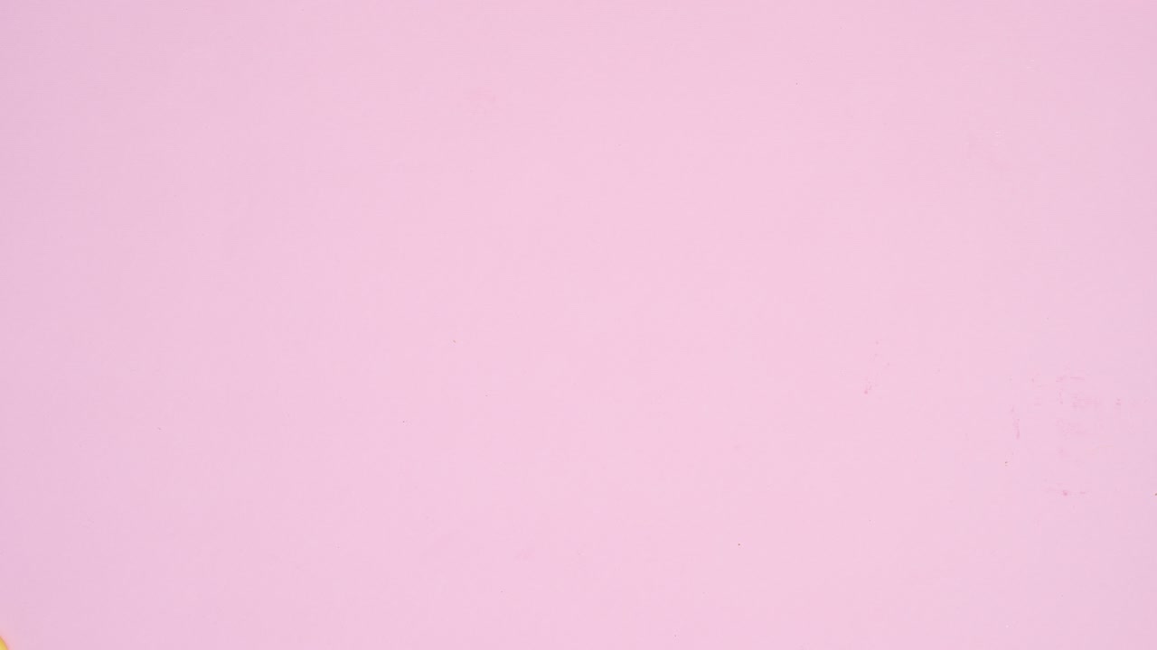 Candies chocolates, gummy candies and lollypops appear on left and right side of pastel pink background. Stop motion animation flat lay