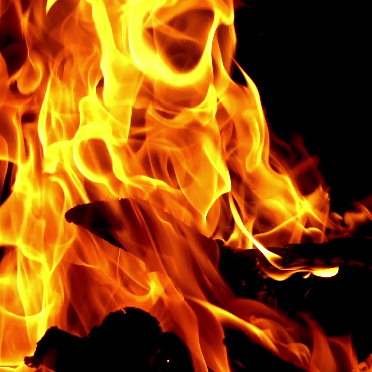 Slow motion of fire at bonfire in the dark, closeup. Bonfire sparks and hot embers at night.