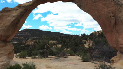 flying under royal arch, natural sandstone rock formation, shiprock, navajo nation, new mexico usa, drone aerial view