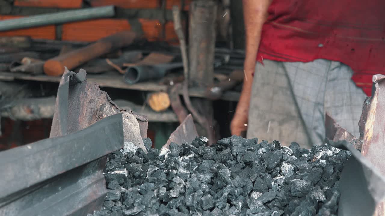 금속 작업을 위해 석탄이 뜨거워지기를 기다리는 대장장이