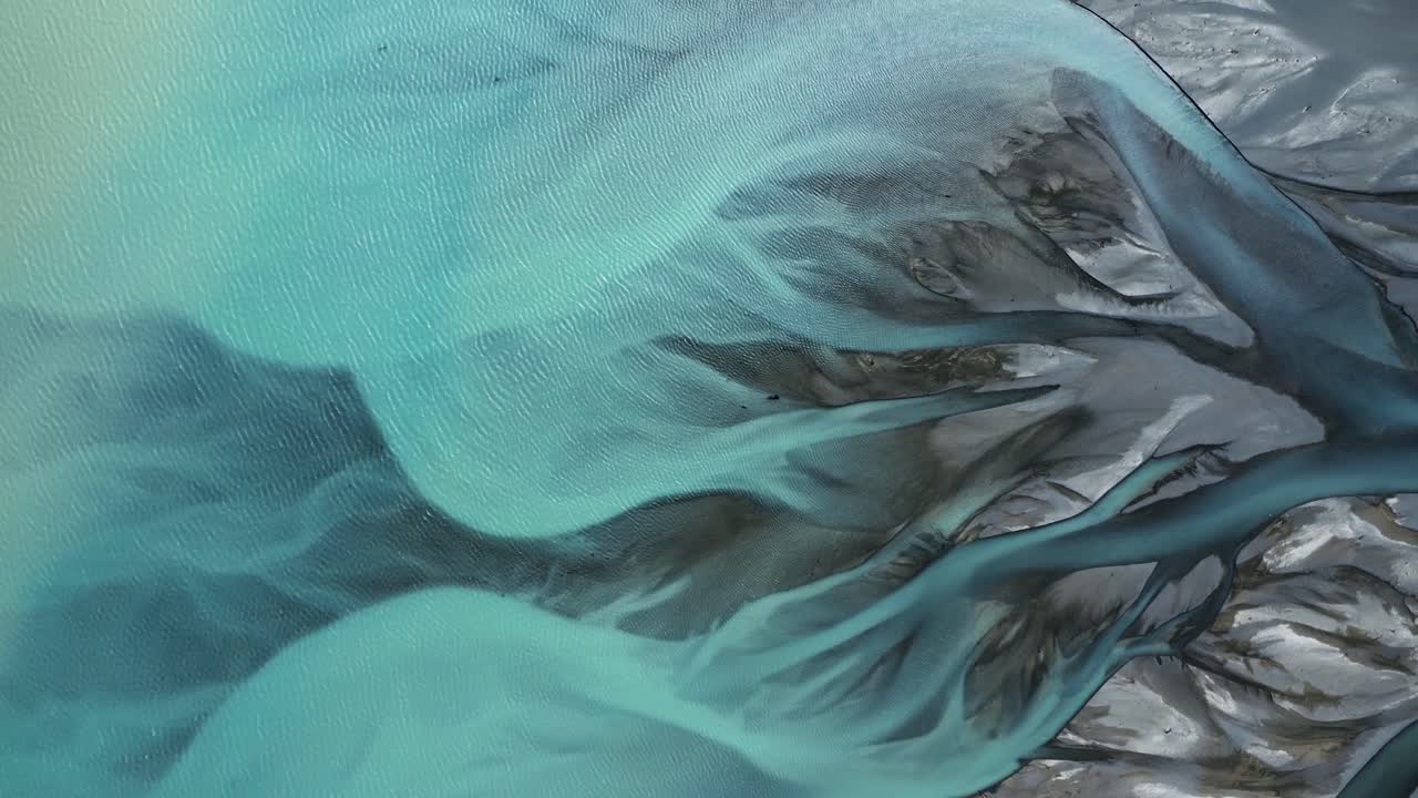 Top down drone shot of Gorgeous Glacial Blue Braided Tasman River flowing into Lake Pukaki like abstract art, New Zealand