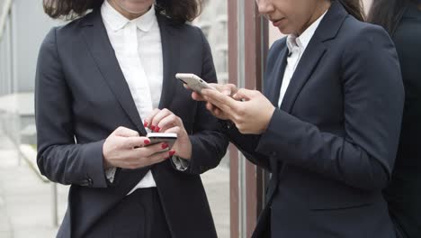 mujeres de negocios serias que usan teléfonos inteligentes