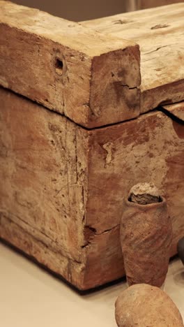 ataúd de madera rodeado de artefactos históricos de cerámica
