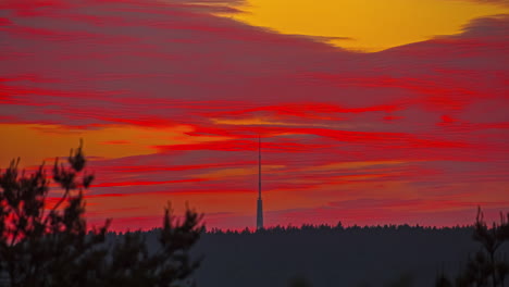 time lapse of a tall radio tower in the background of the video under an incredible reddish sunset with clouds