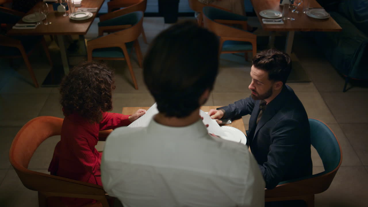 Waiter serving multiethnic couple in cafe bar. Romantic partners ordering dinner