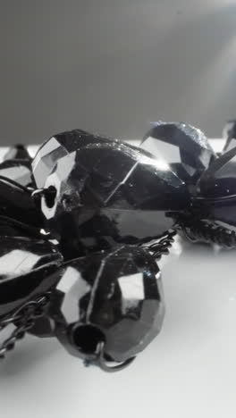 collar de piedras preciosas negras brillantes en una superficie blanca con una llamarada de luz radiante