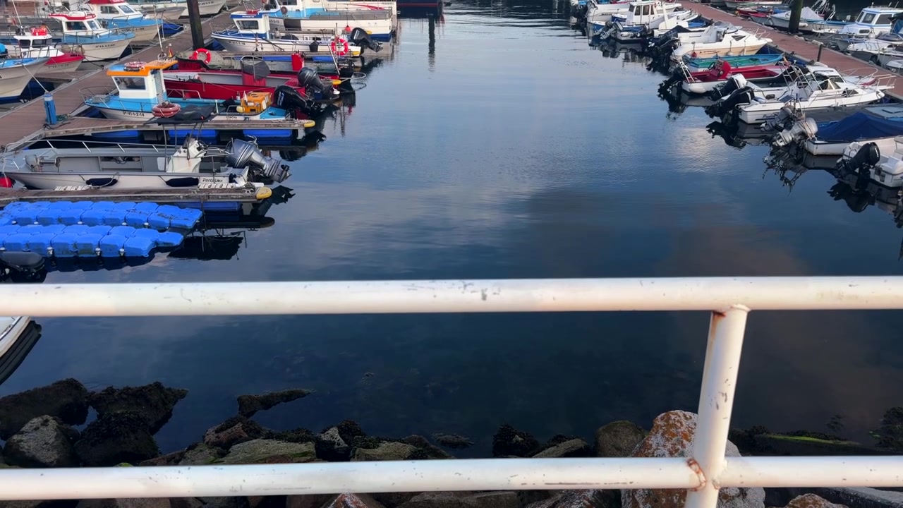 Aerial - Small boats moored at pontoons in Portonovo marina beside a rocky breakwater Sanxenxo
