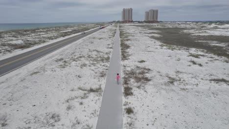 mujer caminando por el carril bici de la playa vestida de rosa haciendo ejercicio en el golfo de méxico