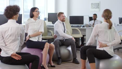 businesspeople exercising on fitballs at workplace