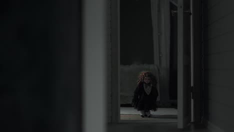 small creepy girl doll standing in the middle of a door frame, staring at the camera
