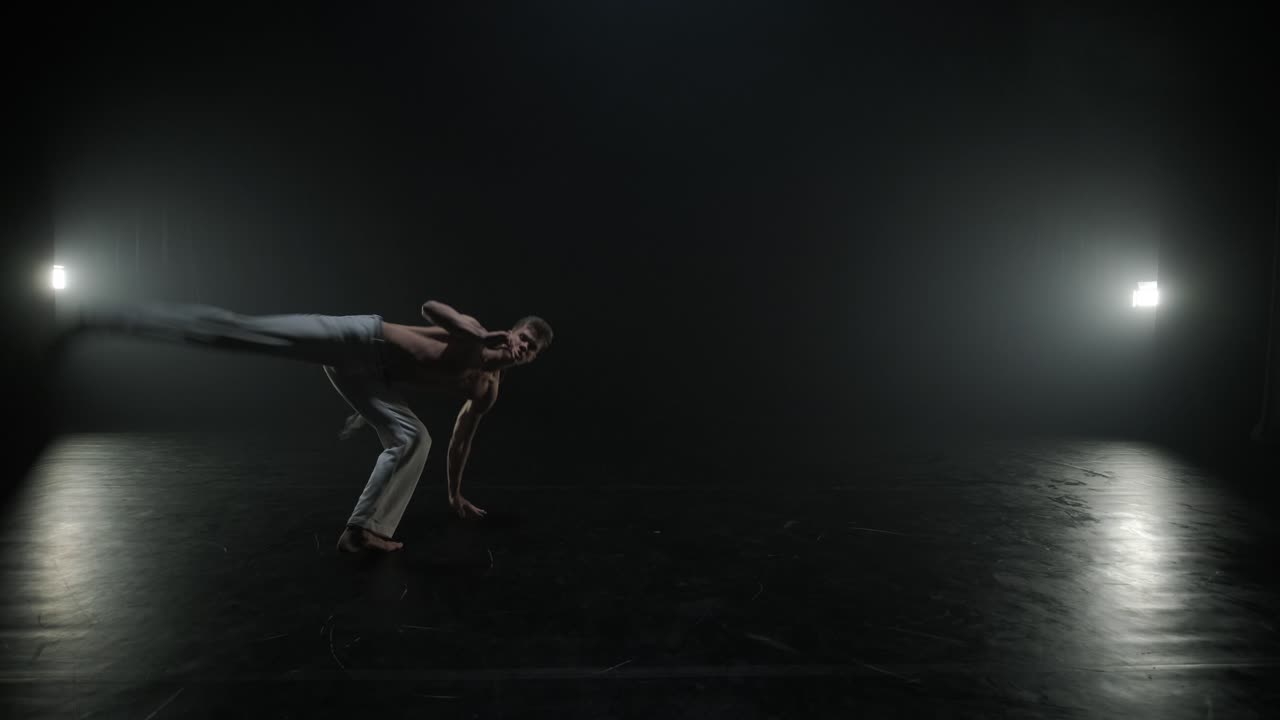 Lottatori di Capoeira che eseguono mosse dinamiche sul palco. Arti marziali, danza e acrobazie in azione. Atleti a torso nudo che mostrano forza, flessibilità e tecnica sotto i riflettori