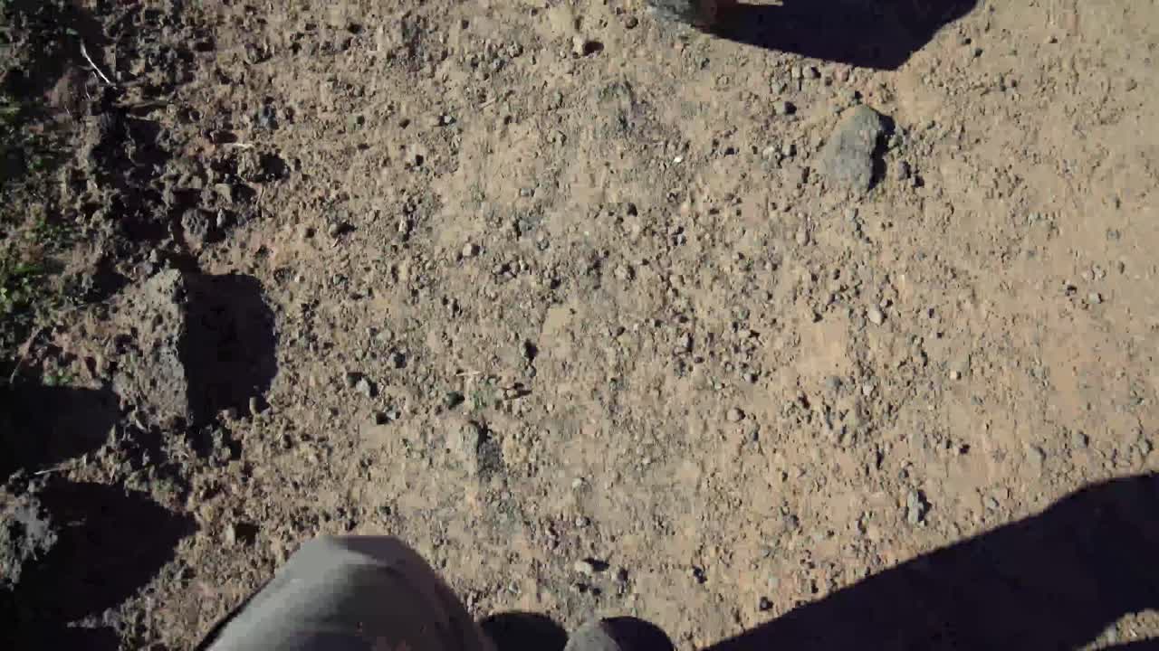la cámara mira hacia abajo a los pies de un hombre con botas de montaña caminando por la arena en el suroeste de estados unidos
