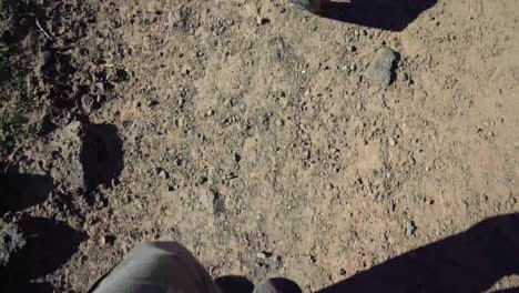 la cámara mira hacia abajo a los pies de un hombre con botas de montaña caminando por la arena en el suroeste de estados unidos