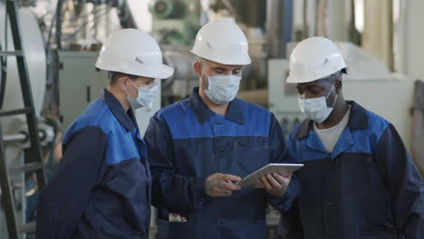 slowmo of plant workers with tablet talking
