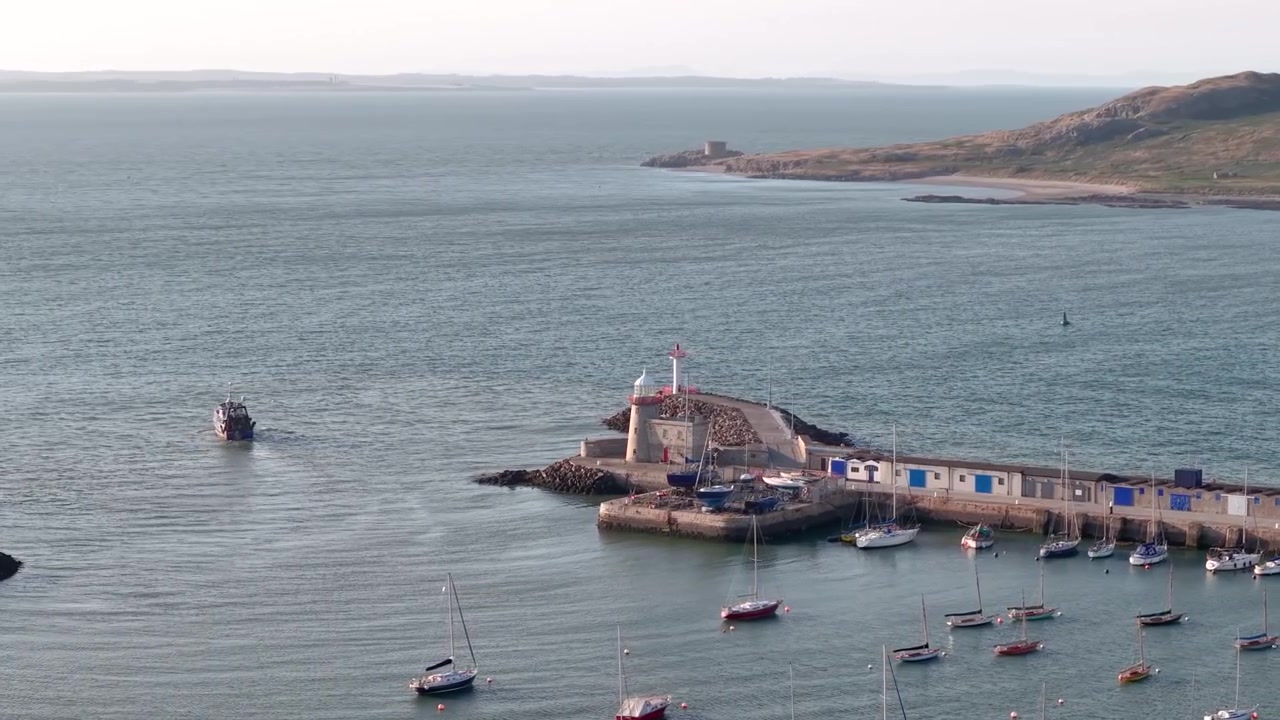 Faro di Howth e porto turistico al tramonto con barche e Ireland's Eye, vista aerea con drone.