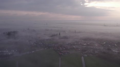 Wide-shot-of-Burgum-Friesland-covered-in-dense-fog-during-sunrise,-aerial