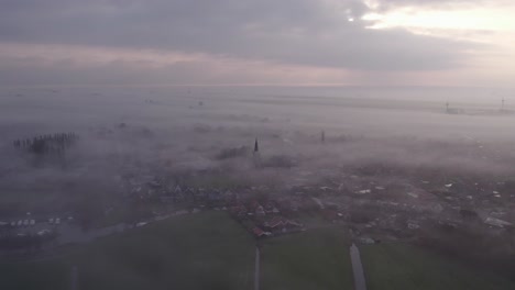 tomada amplia de burgum friesland cubierta de densa niebla durante el amanecer, aérea