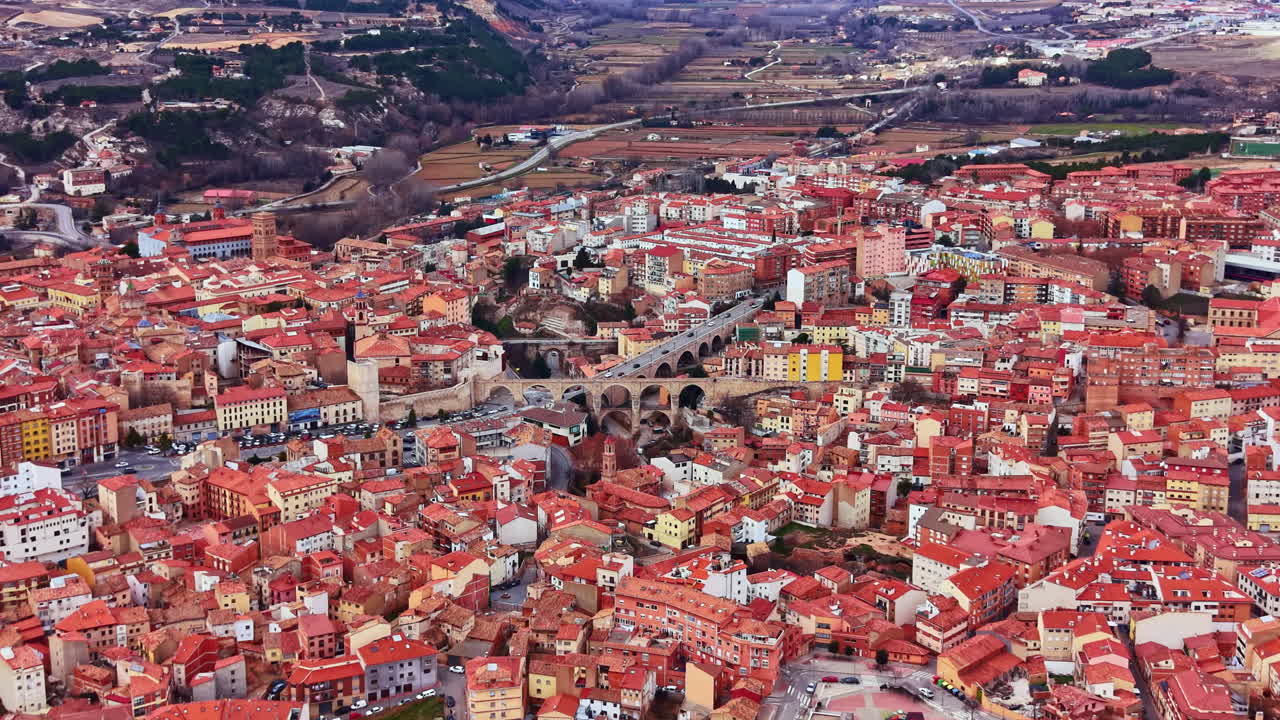 Udsigt over en by med røde tegltage i Spanien, der viser bygninger, gader og bakker om dagen.
