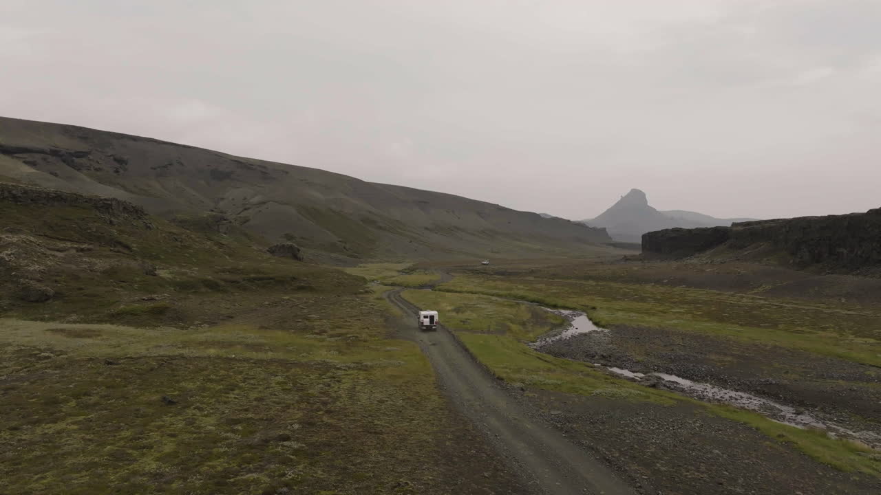 Static drone shot of a overlanding vehicle driving away from the camera in Iceland