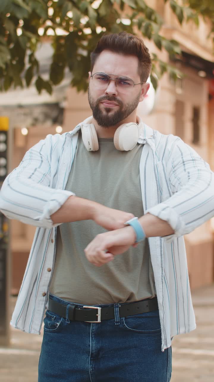 Upset young caucasian man tourist showing double thumbs down expressing discontent on city street
