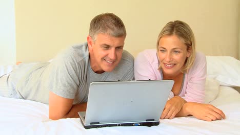 una pareja acostada mirando una computadora portátil