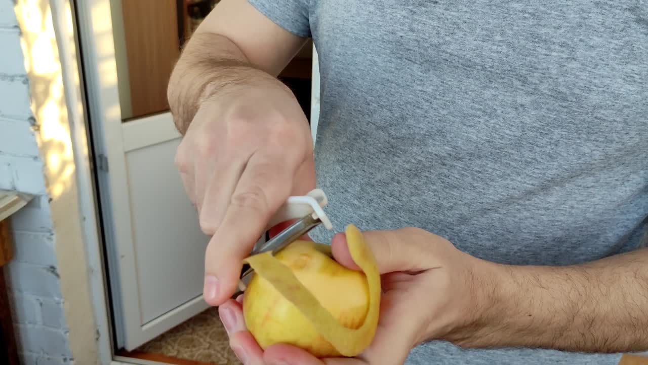 Hombre pelando una manzana con un pelador de verduras