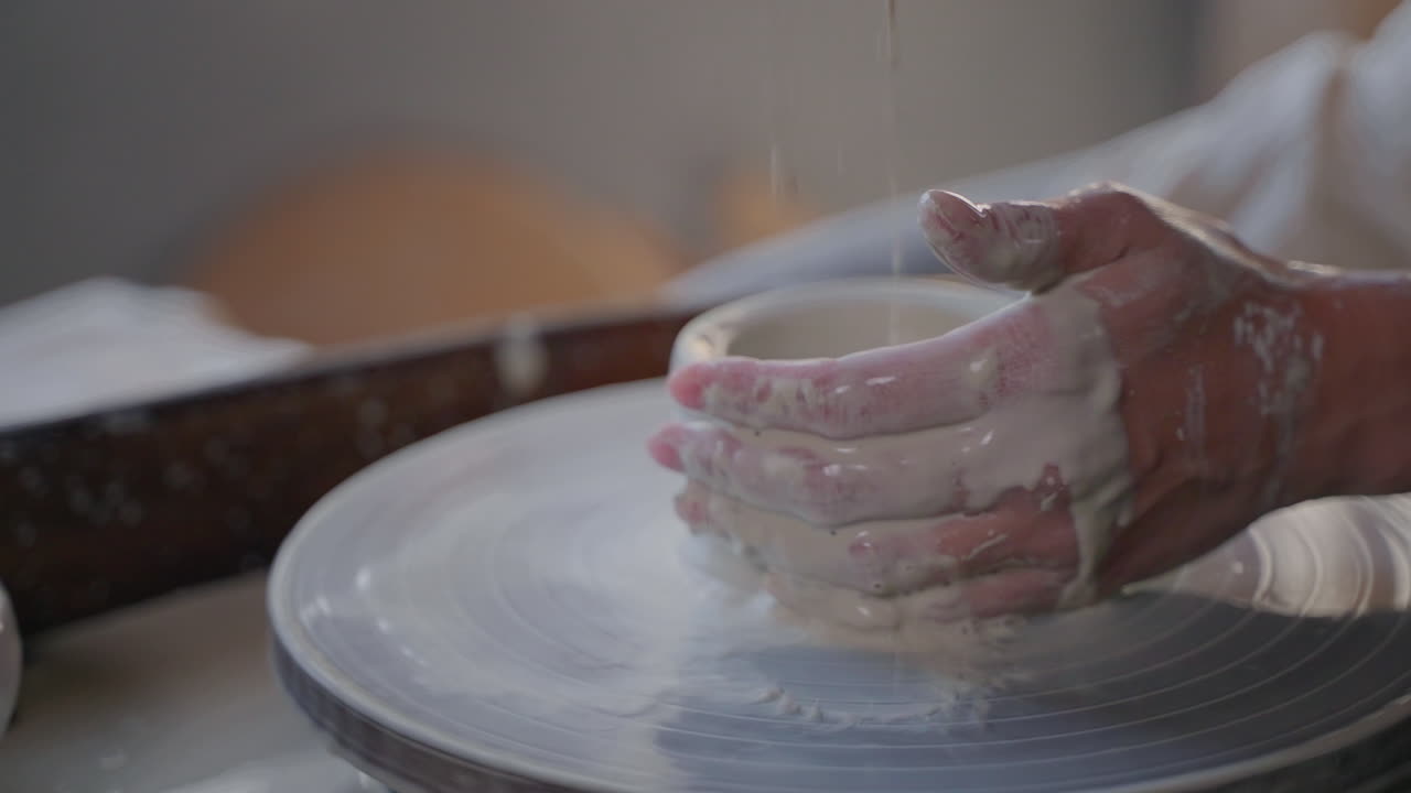 Woman shaping a bowl on a pottery wheel