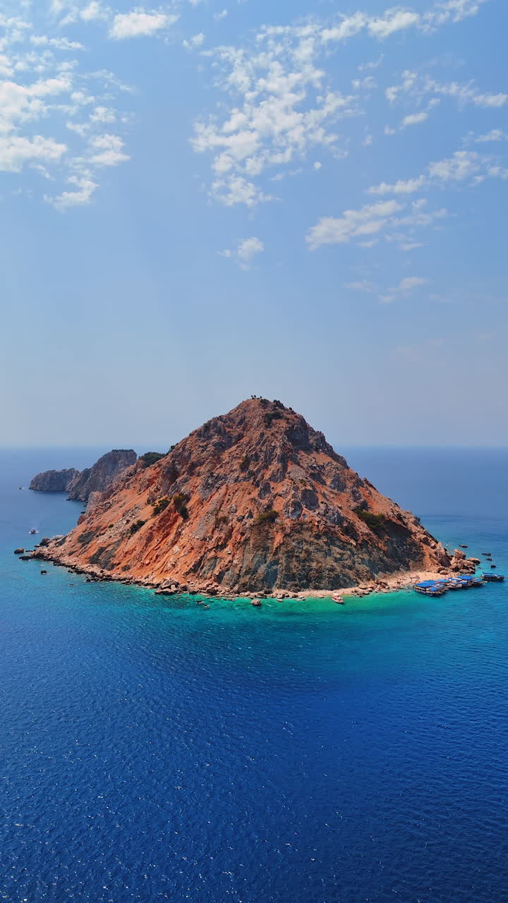 Pyramid-shaped island surrounded by the azure waterscape. Drone flight near the Suluada island in the Mediterranean of Turkey. Vertical video