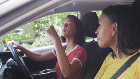 biracial sisters sitting in car and having driving lesson, in slow motion