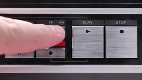 Extreme-close-up-of-buttons-on-an-old-antique-or-vintage-VCR-pushing-fast-forward-and-holding-the-finger-on-in