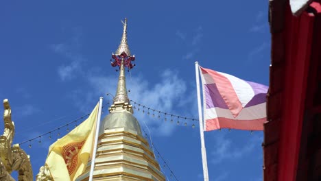 flags waving beside a golden buddhist pagoda