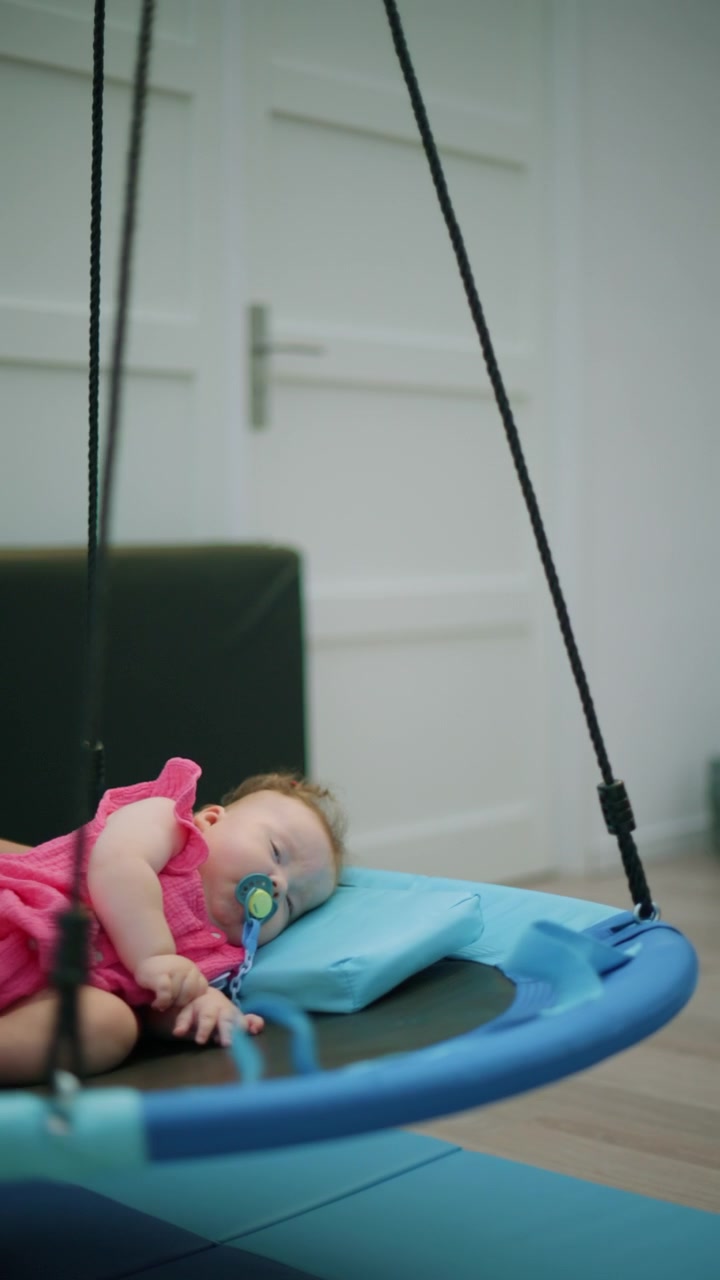 Baby girl receiving support from hands during a sensory therapy session in an indoor pool, aiding development and well being