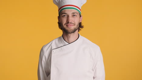 caucasian chef in front of camera on yellow background.