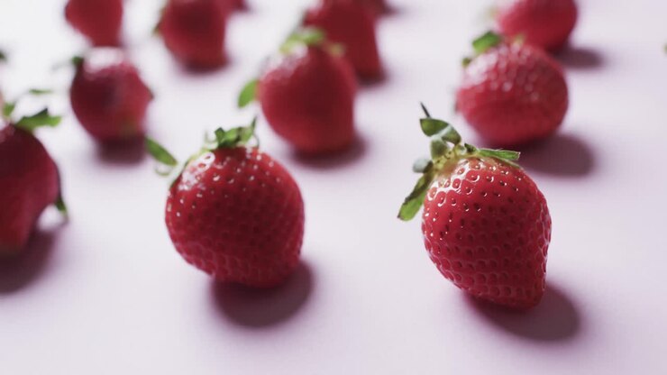 Video of rows of strawberries with copy space over pink background