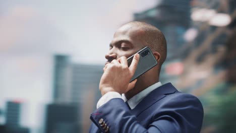 360 degree street shot: portrait of confident black businessman talking on smartphone in city. successful african american entrepreneur using mobile to make a phone call. tracking moving around shot