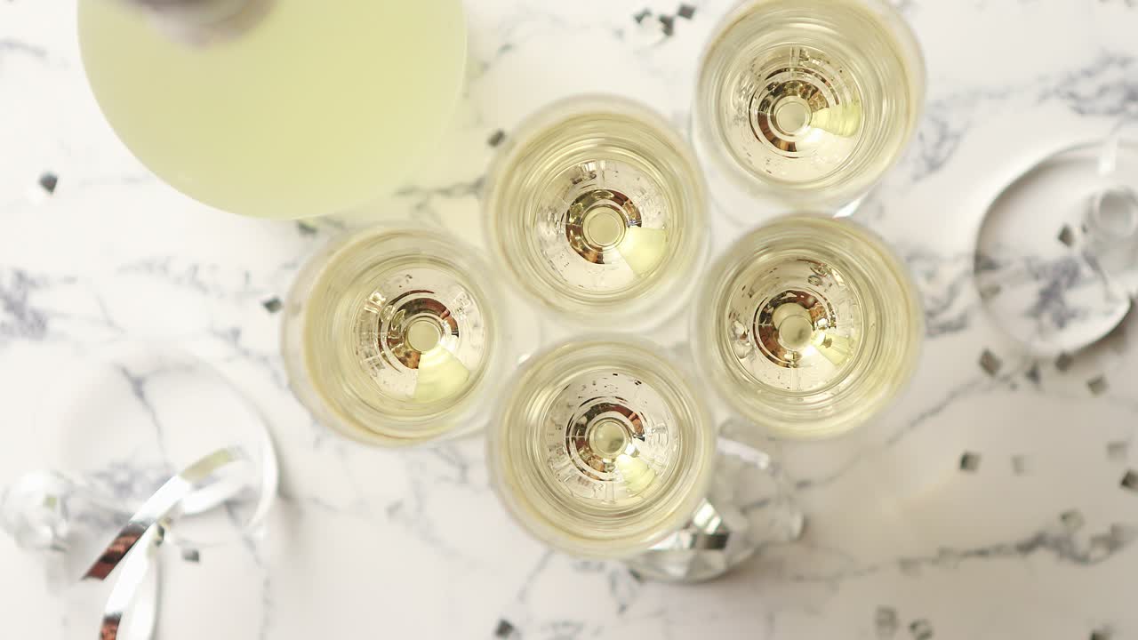 Bicchieri da champagne e bottiglia posti su sfondo di marmo bianco.