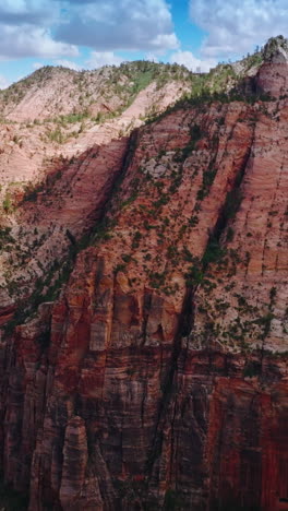 approaching enormous pink rocks zion canyon in utah, united states. stunning mountains at the backdrop of blue cloudy sky. vertical video