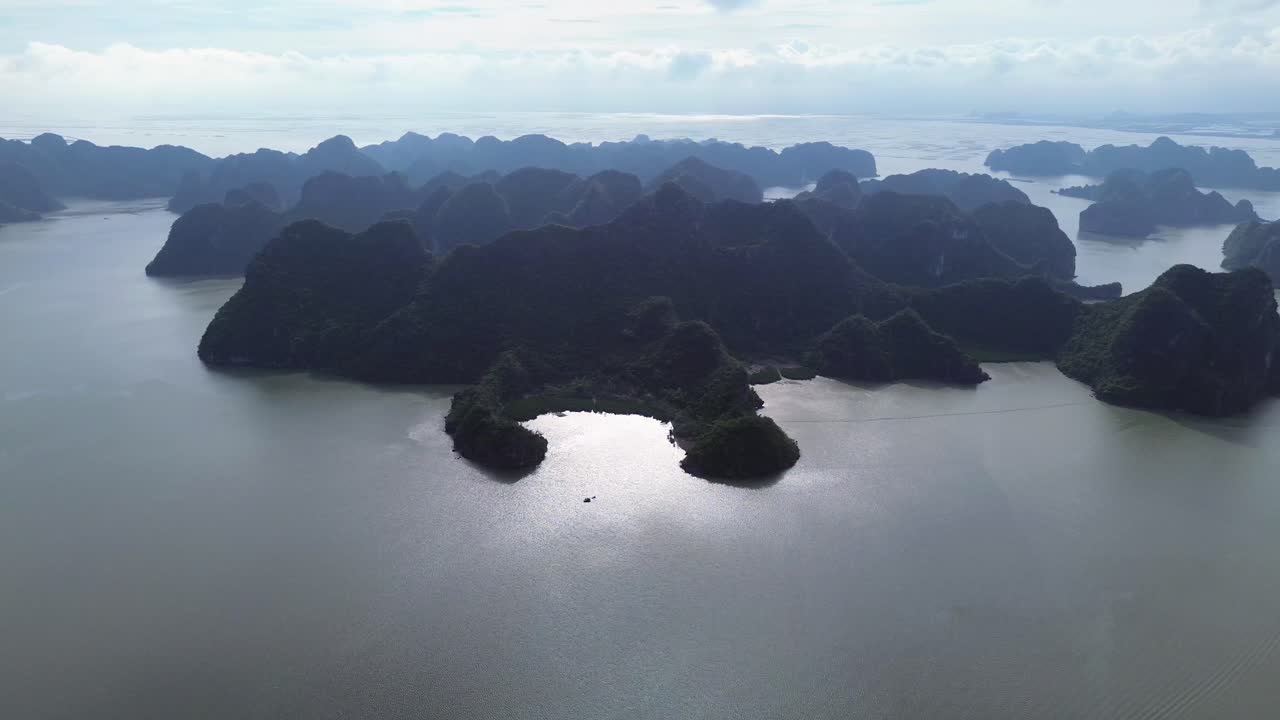 Cảnh quay lia phải từ trên cao trên mặt nước xanh biếc và những hòn đảo nhỏ dốc đứng của Đảo Cát Bà, Việt Nam