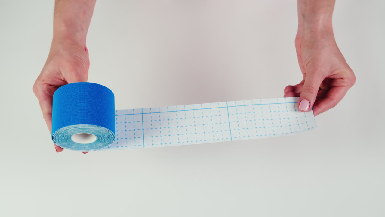 Kinesiology medical taping, doctor Physical therapist applying elastic surgical tape to patient body, treating injured knee young athlete.Post traumatic rehabilitation, sport physical therapy recovery